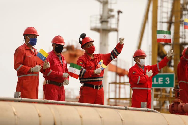 Workers of the state-oil company Pdvsa holding Iranian and Venezuelan flags greet during the arrival of the Iranian tanker ship "Fortune" at El Palito refinery in Puerto Cabello