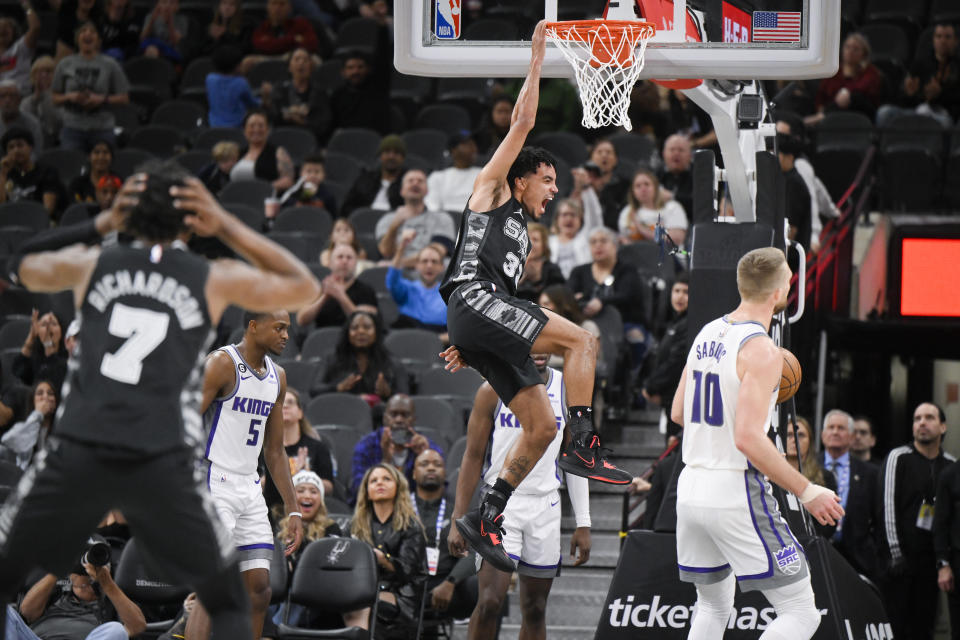 San Antonio Spurs' Tre Jones, center, dunks during the first half of an NBA basketball game against the Sacramento Kings, Sunday, Jan. 15, 2023, in San Antonio. (AP Photo/Darren Abate)