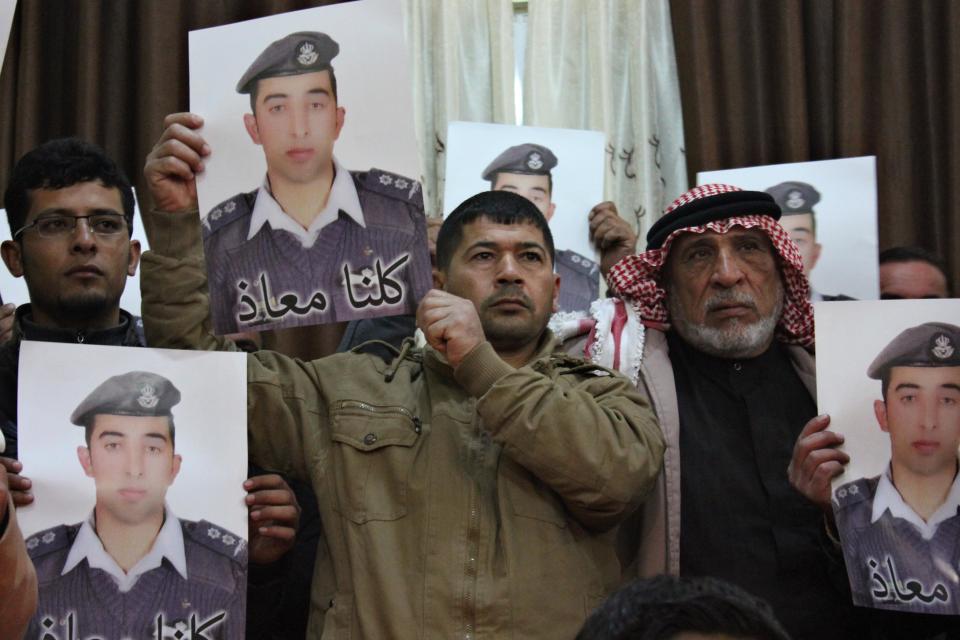 Relatives of Islamic State captive Jordanian pilot Muath al-Kasaesbeh hold his poster as they take part in a rally in his support at the family's headquarters in the city of Karak, January 31, 2015. The words on the portrait reads, "We are all Muath." REUTERS/Stringer (JORDAN - Tags: POLITICS CIVIL UNREST TPX IMAGES OF THE DAY)