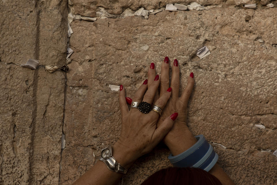 A woman prays at the Western Wall, the holiest site where Jews can pray, in the shadow of a wooden pedestrian bridge connecting the wall to the Al Aqsa Mosque compound, in Jerusalem's Old City, Tuesday, July 20, 2021. Experts say the rickety bridge that allows access to the Holy Land's most sensitive religious site is at imminent risk of collapse. But the shrine's delicate position at the epicenter of the Israeli-Palestinian conflict prevents it from being repaired -- raising fears of another disaster just months after 45 people were killed in a stampede at an ultra-Orthodox Jewish shrine where organizers had also ignored years of safety warnings. (AP Photo/Maya Alleruzzo)