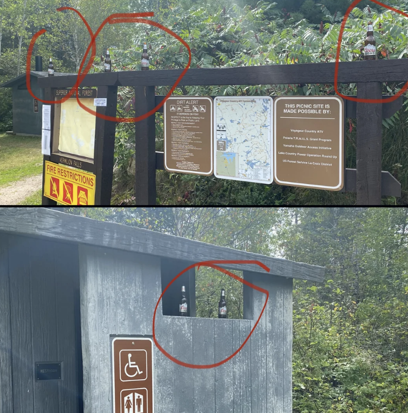 Several beer bottles are placed on signs and structures in a park area. The signs include maps, park alerts, and guidelines