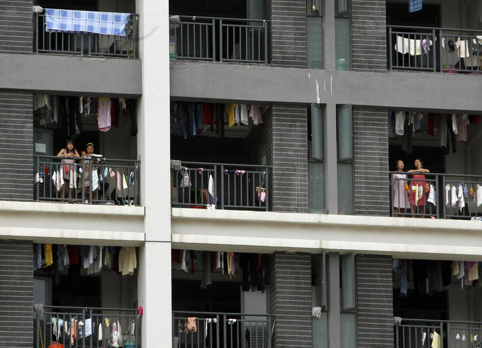 FILE-In this Wednesday, May 26, 2010, file photo, employees stand on the balconies of a residential house at the Foxconn complex in Shenzhen, China. Foxconn, the company that makes Apple’s iPhones suspended production at a factory in China on Monday, Sept. 24, 2012, after a brawl by as many as 2,000 employees at a dormitory injured 40 people. The fight, the cause of which was under investigation, erupted Sunday night at a privately managed dormitory near a Foxconn Technology Group factory in the northern city of Taiyuan, the company and Chinese police said. (AP Photo/Kin Cheung, File)