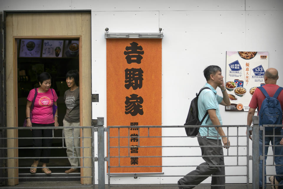 Women stand in the entrance of a Yoshinoya restaurant that has been boarded up in Hong Kong, Friday, Oct. 25, 2019. Banks, retailers, restaurants and travel agents in Hong Kong with ties to mainland China or perceived pro-Beijing ownership have fortified their facades over apparent concern about further damage after protesters trashed numerous businesses following a recent pro-democracy rally. (AP Photo/Mark Schiefelbein)