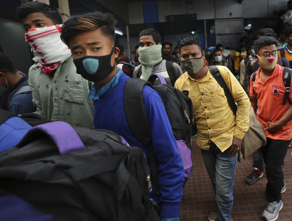 People wearing face masks as a precaution against the coronavirus arrive at a train station in Bengaluru, India, Monday, Feb. 22, 2021. Cases of COVID-19 are increasing in some parts of India after months of a steady nationwide decline, prompting authorities to impose lockdowns and other virus restrictions. (AP Photo/Aijaz Rahi)