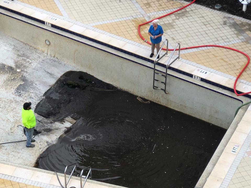 Property manager Jori Holtman watches as gunk from Hurricane Ian is removed from a pool at a downtown Fort Myers condo complex along the Caloosahatchee River.
