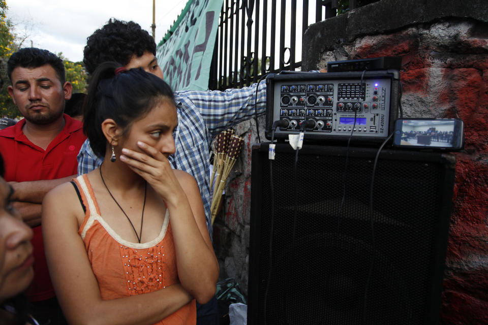 Laura Zuniga watches a video on a mobile phone as the murderers of her mother, the Honduran indigenous and environmental rights activist Berta Caceres, are found guilty, outside the court room in Tegucigalpa, Honduras, Thursday, Nov. 29, 2018. Seven of the eight accused were found guilty and will be sentenced on January 2019. (AP Photo/Fernando Antonio)