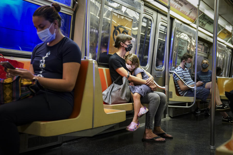 FILE - This photo from Monday, Aug. 17, 2020, shows riders on a subway train wearing protective masks due to COVID-19 concerns in New York. The Metropolitan Transportation Authority on Friday launched a campaign that has celebrities including Jerry Seinfeld, Whoopi Goldberg, and Awkwafina making the announcements heard at subway stations, on trains, and buses. (AP Photo/John Minchillo, File)