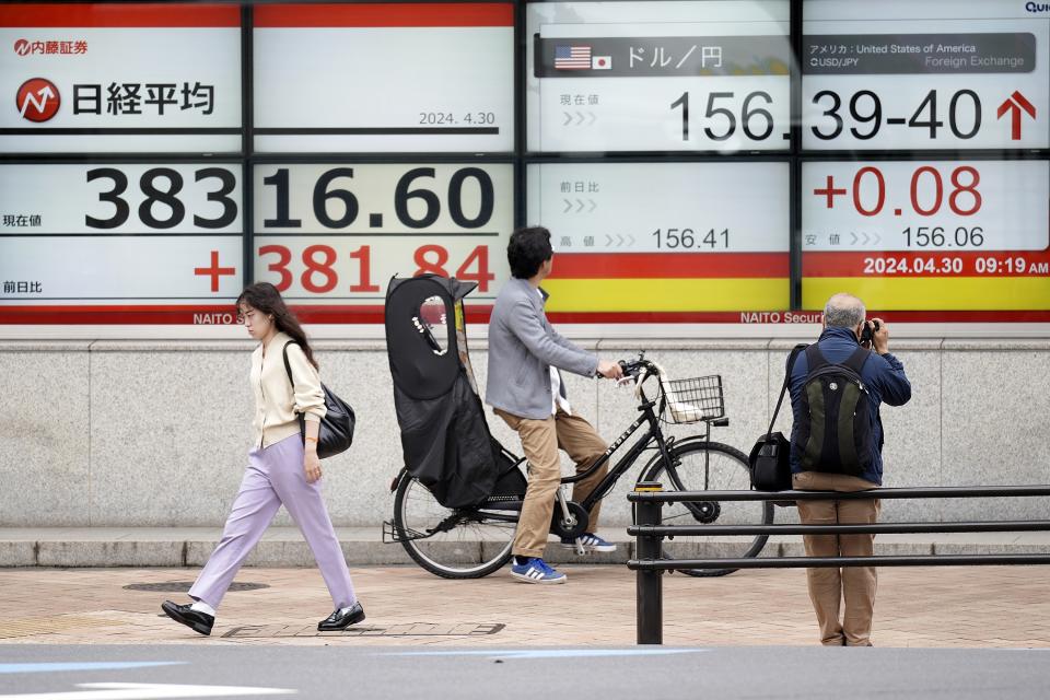 People pass by an electronic stock board showing Japan's Nikkei 225 index, left, and U.dollar/Japanese yen conversion rate at a securities firm Tuesday, April 30, 2024, in Tokyo. Asian shares mostly rose Tuesday, as investors kept their eyes on potentially market-moving reports expected later this week.(AP Photo/Eugene Hoshiko)