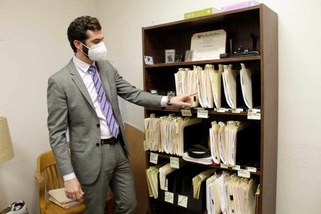 Public defender Drew Flood with the nonprofit law firm Metropolitan Public Defender looks his files for the criminal cases. Flood is carrying 100 cases and says he sometimes can’t remember details such as what is in the client’s police report or what plea deal is being offered. (AP Photo/Gillian Flaccus)