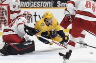 Nashville Predators left wing Tanner Jeannot (84) reaches for the puck in front of Carolina Hurricanes goaltender Alex Nedeljkovic (39) during the second period of an NHL hockey game Saturday, May 8, 2021, in Nashville, Tenn. (AP Photo/Mark Zaleski)