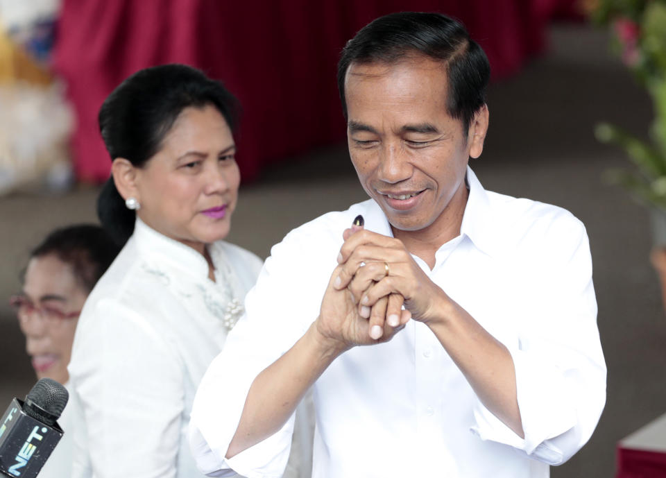 Indonesian President Joko "Jokowi" Widodo shows his inked finger as his wife Iriana looks on after casting their ballots during the election at a polling station in Jakarta, Indonesia, Wednesday, April 17, 2019. Tens of millions of Indonesians were voting in presidential and legislative elections Wednesday after a campaign that pitted the moderate incumbent against an ultranationalist former general whose fear-based rhetoric warned the country would fall apart without his strongman leadership. (AP Photo/Dita Alangkara)