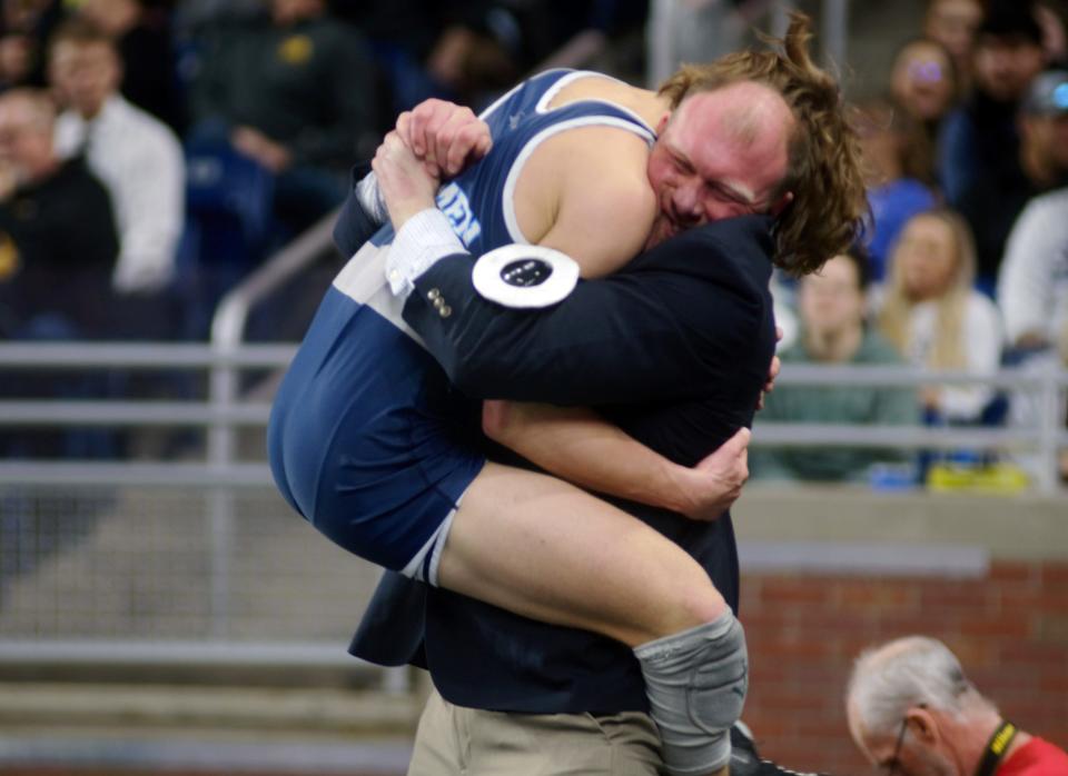 Petoskey's Trevor Swiss leads into his father, Josh Swiss', arms following his completed Division 2 150-pound state championship match.