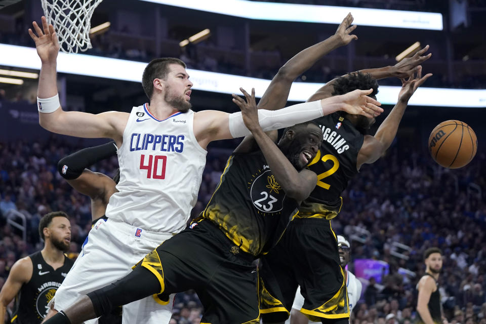 Los Angeles Clippers center Ivica Zubac (40) reaches for the ball next to Golden State Warriors forward Draymond Green (23) and forward Andrew Wiggins during the first half of an NBA basketball game in San Francisco, Wednesday, Nov. 23, 2022. (AP Photo/Jeff Chiu)