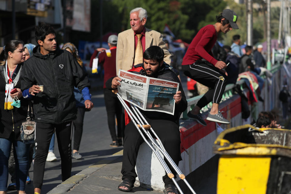 A protesters reads a copy of the "Tuk-Tuk" newspaper, in Tahrir Square, Baghdad, Iraq, Wednesday, Nov. 20, 2019. A small group of Iraqi volunteers is working in secrecy to produce the newspaper that aims to be the voice of the largest grassroots protest movement in the country’s modern history. Its editors say the newspaper is vital amid shutdowns of the internet, filling a void left by mainstream Iraqi journalists who either back the government or fear retaliation. (AP Photo/Hadi Mizban)