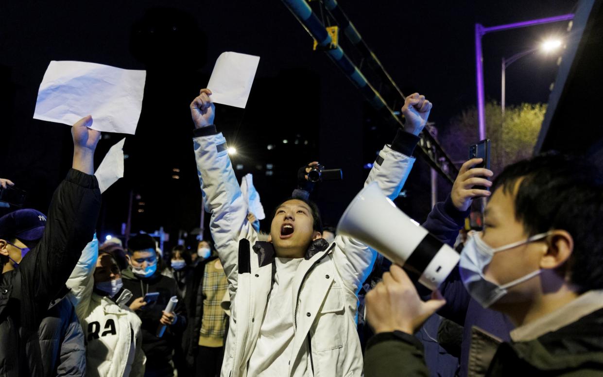 People hold white sheets of paper in protest over Covid restrictions in Beijing - REUTERS