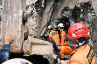 Rescuers search for victims at the ruin of a building damaged by an earthquake in Mamuju, West Sulawesi, Indonesia, Saturday, Jan. 16, 2021. Damaged roads and bridges, power blackouts and lack of heavy equipment on Saturday hampered Indonesia's rescuers after a strong and shallow earthquake left a number of people dead and injured on Sulawesi island. (AP Photo/Sadly Ashari Said)