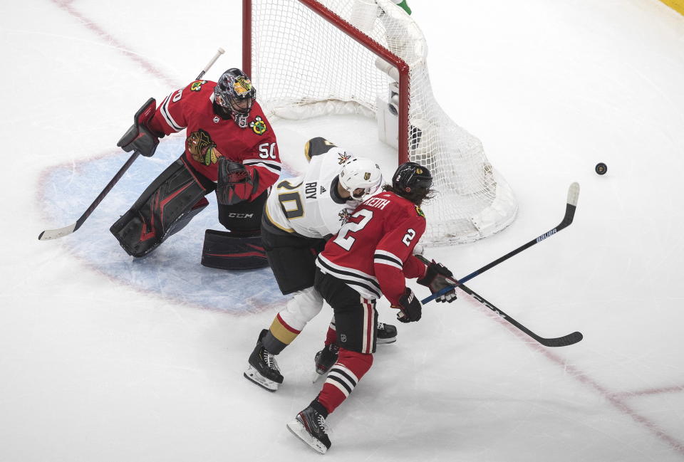Vegas Golden Knights' Nicolas Roy (10) and Chicago Blackhawks' Duncan Keith (2) chase the rebound from goalie Corey Crawford (50) during the second period of an NHL hockey Stanley Cup first-round playoff series, Saturday, Aug. 15, 2020, in Edmonton, Alberta. (Jason Franson/The Canadian Press via AP)