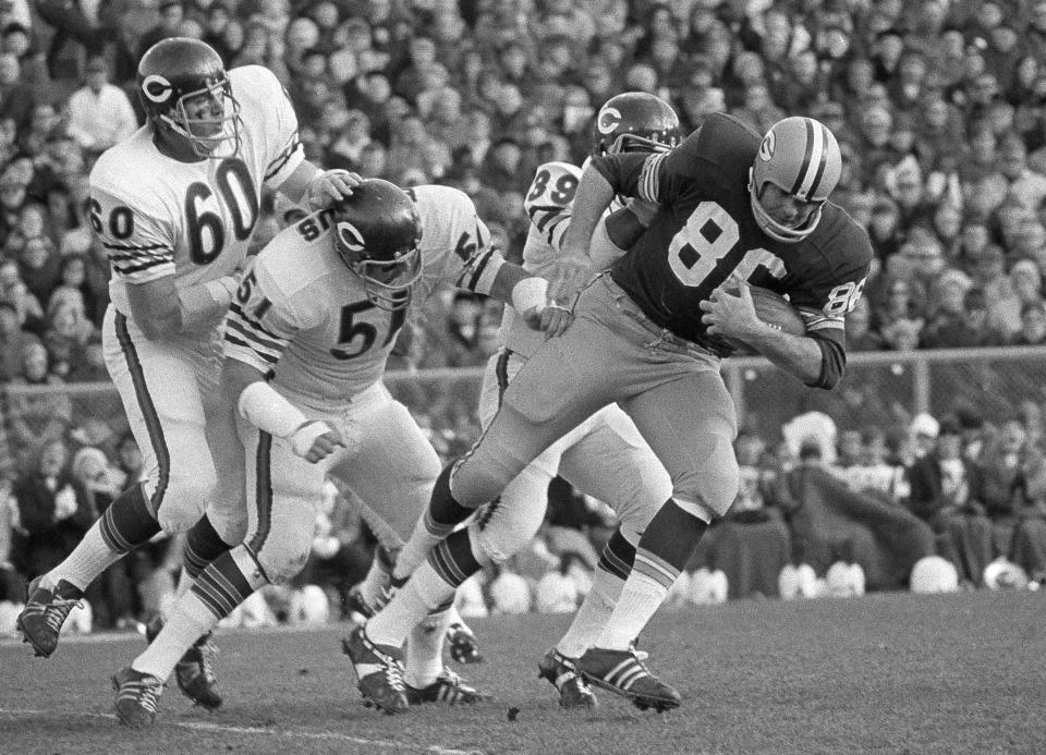 FILE - Chicago Bears' Lee Roy Caffee (60), Dick Butkus (51) and Phil Clark (39) try to stop Green Bay Packers' John Hilton (86) after a pass reception during an NFL football game Nov. 15, 1970, in Green Bay, Wis. Butkus, a fearsome middle linebacker for the Bears, has died, the team announced Thursday, Oct. 5, 2023. He was 80. According to a statement released by the team, Butkus' family confirmed that he died in his sleep overnight at his home in Malibu, Calif. (AP Photo, File)