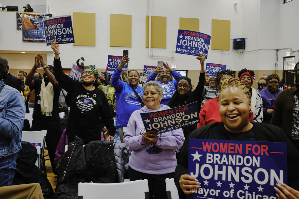 People hold signs and cheer during a 