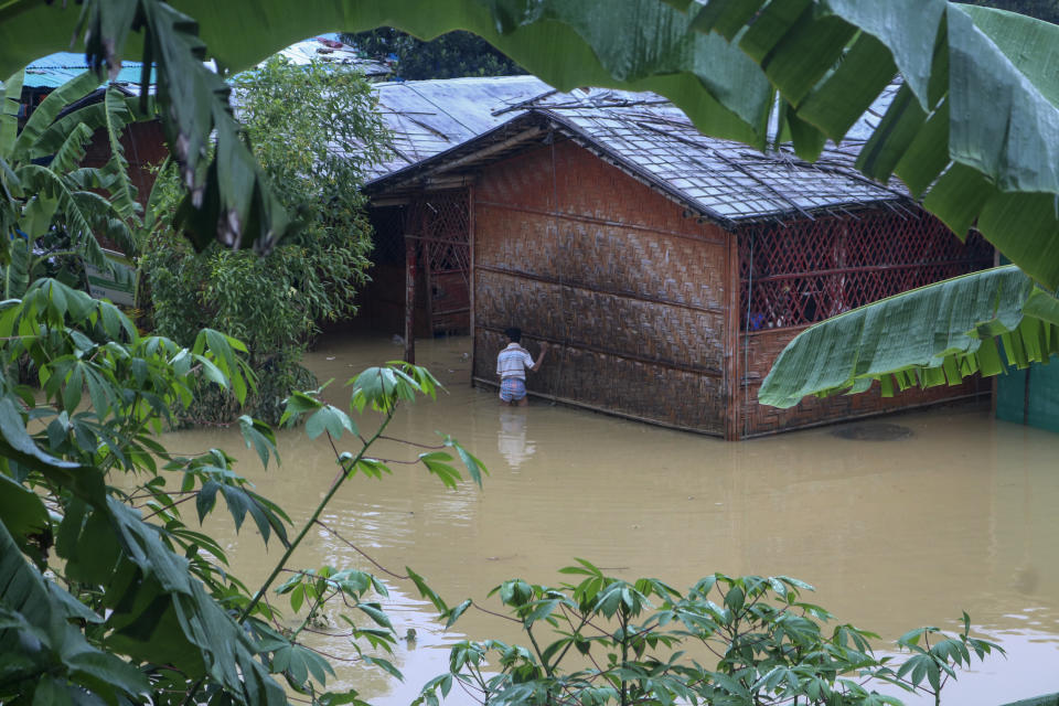 A Rohingya refugee walks through flood water following heavy rains at the Rohingya refugee camp in Kutupalong, Bangladesh, Wednesday, July 28, 2021. Days of heavy rains have brought thousands of shelters in various Rohingya refugee camps in Southern Bangladesh under water, rendering thousands of refugees homeless. (AP Photo/ Shafiqur Rahman)