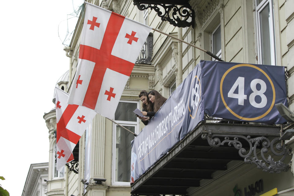 Two women read a paper on the balcony of the headquarters of presidential candidate Salome Zurabishvili during the presidential election in Tbilisi, Georgia, Sunday, Oct. 28, 2018. Sunday's election will be the last time residents of the former Soviet republic of Georgia get to cast a ballot for president, that's if any of the 25 candidates gets an absolute majority. (AP Photo/Shakh Aivazov)