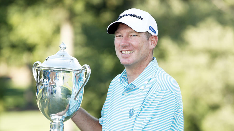 Jim Herman smiles and celebrates with the trophy.