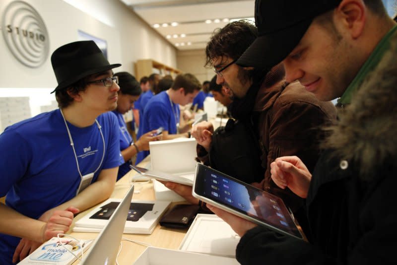 Apple employee Benjamin Salasek (L) talks with new iPad owner Miguel Bullon (C) as Pedro Cordero checks out his new iPad at Apple Computer's North Michgan Avenue store in Chicago on April 3, 2010. File Photo by Brian Kersey/UPI