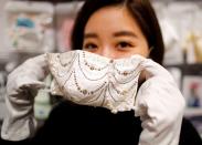 An employee of Cox Co, the operation company of the face-mask speciality shop Mask.com, shows off a luxury face mask decorated with the diamond, platinum and Swarovski crystals in Tokyo