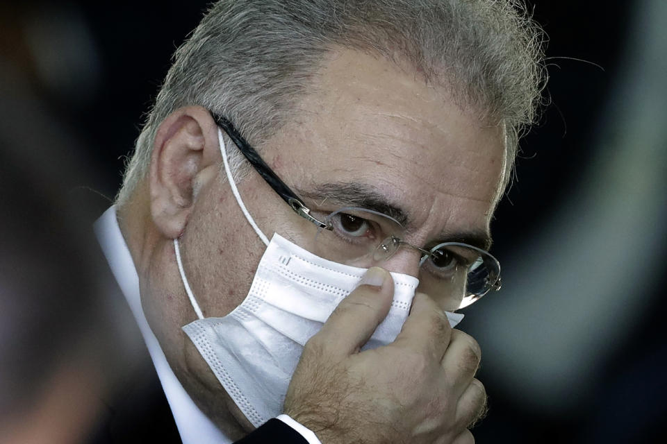 FILE - In this March 24, 2021 file photo, Brazil's new Health Minister Marcelo Queiroga adjusts his protective face mask before the start of a press conference, at the presidential residence Alvorada Palace in Brasilia, Brazil. Queiroga, the fourth man to occupy the health ministry post during the COVID-19 pandemic, is a doctor who speaks about the need to boost vaccine supply, consults with scientists and has so far displayed the autonomy to promote mask use and social distancing. (AP Photo/Eraldo Peres, File)