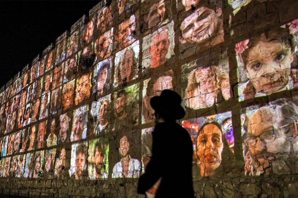 An Ultra-Orthodox Jewish man walks outside the walls of the old city of Jerusalem, on which are projected pictures of the hostages abducted by Palestinian militants on the October 7 attack and currently held in the Gaza Strip, on Nov. 6, 2023, amid the ongoing battles between Israel and the militant group Hamas.