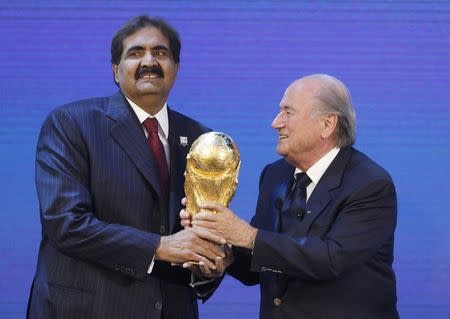 FIFA president Sepp Blatter (R) hands over a copy of the World Cup to Qatar's Emir Sheikh Hamad bin Khalifa al Thani after the announcement that Qatar is going to be host nation for the FIFA World Cup 2022, in Zurich December 2, 2010. REUTERS/Christian Hartmann
