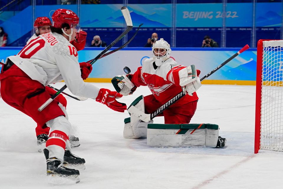 Russian Olympic Committee's Dmitri Voronkov (10) reaches for the puck after a deflection by Denmark goalkeeper Frederik Dichow, right, during a preliminary round men's hockey game at the 2022 Winter Olympics, Friday, Feb. 11, 2022, in Beijing. (AP Photo/Matt Slocum)