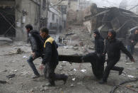 <p>Syrian civil defence volunteers carry away an injured man after reported regime air strikes in the rebel-held town of Jisreen, in the besieged Eastern Ghouta region on the outskirts of the capital Damascus, on Feb. 8, 2018. (Photo: Abdulmonam Eassa/AFP/Getty Images) </p>