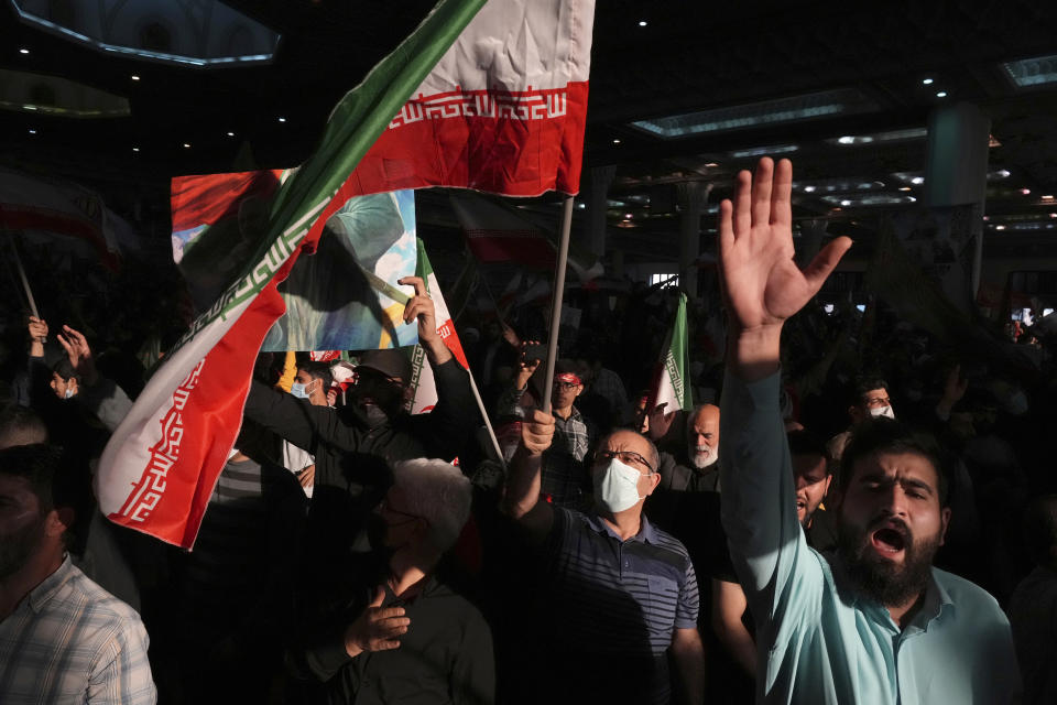 Mourners chant slogans as they wave Iranian national flag during a ceremony marking anniversary of the death of the late Revolutionary Guard Gen. Qassem Soleimani, who was killed in Iraq in a U.S. drone attack in 2020, at Imam Khomeini Grand Mosque in Tehran, Iran, Tuesday, Jan. 3, 2023. Iran's President Ebrahim Raisi on Tuesday vowed to avenge the killing of the country's top general on the third anniversary of his death, as the government rallied its supporters in mourning amid months of anti-government protests. (AP Photo/Vahid Salemi)