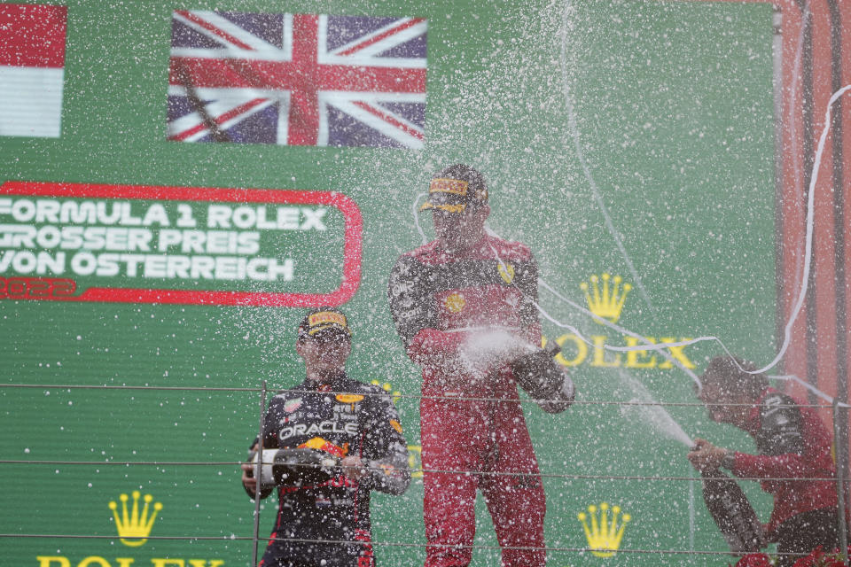 Charles Leclerc (centro) celebra en el podio tras ganar el Gran Premio de Austria en Spielberg, el domingo 10 de julio de 2022. (AP Foto/Matthias Schrader)