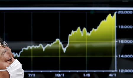 A pedestrian walks past an electronic board showing the graph of the recent fluctuations of the Japan's Nikkei average outside a brokerage in Tokyo April 10, 2015. REUTERS/Yuya Shino