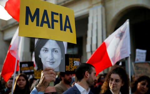 A protester holds a photo of Daphne Caruana Galizia - Credit: Reuters