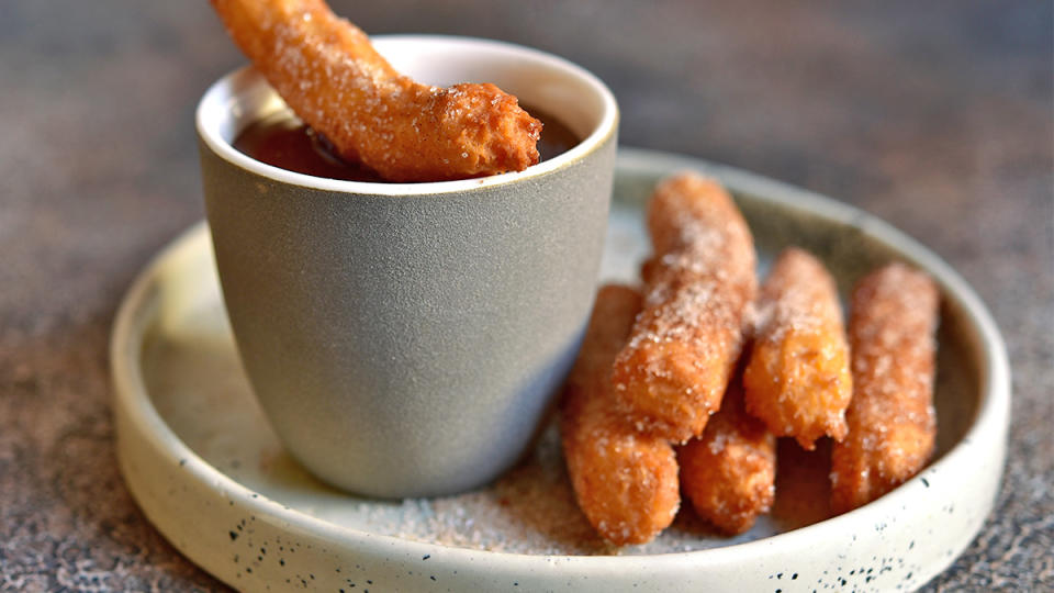 A batch of funnel cake fries with warm chocolate sauce