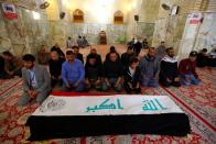 Mourners pray near the coffin of a demonstrator who was killed at anti-government protests in Nassiriya, during the funeral in Najaf