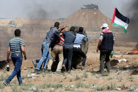 Palestinian demonstrators roll a tire during a protest marking al-Quds Day, (Jerusalem Day), at the Israel-Gaza border, east of Gaza City June 8, 2018. REUTERS/Mohammed Salem