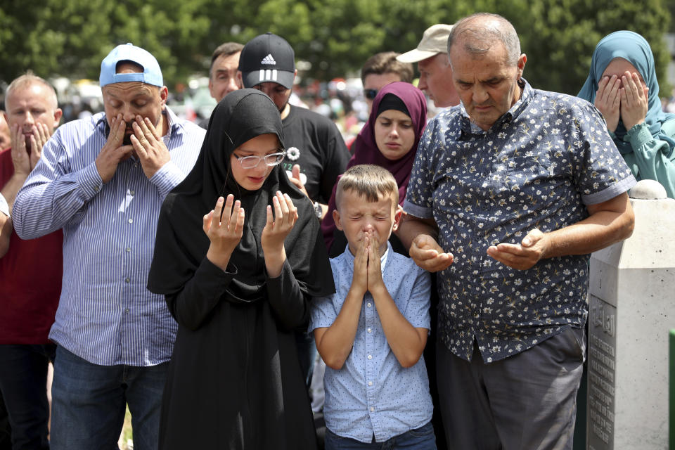 Bosnian muslim family mourns next to the grave during a mass burial of remains of 50 newly identified victims of Srebrenica Genocide in Potocari, Monday, July 11, 2022. Thousands converge on the eastern Bosnian town of Srebrenica to commemorate the 27th anniversary on Monday of Europe's only acknowledged genocide since World War II. (AP Photo/Armin Durgut)