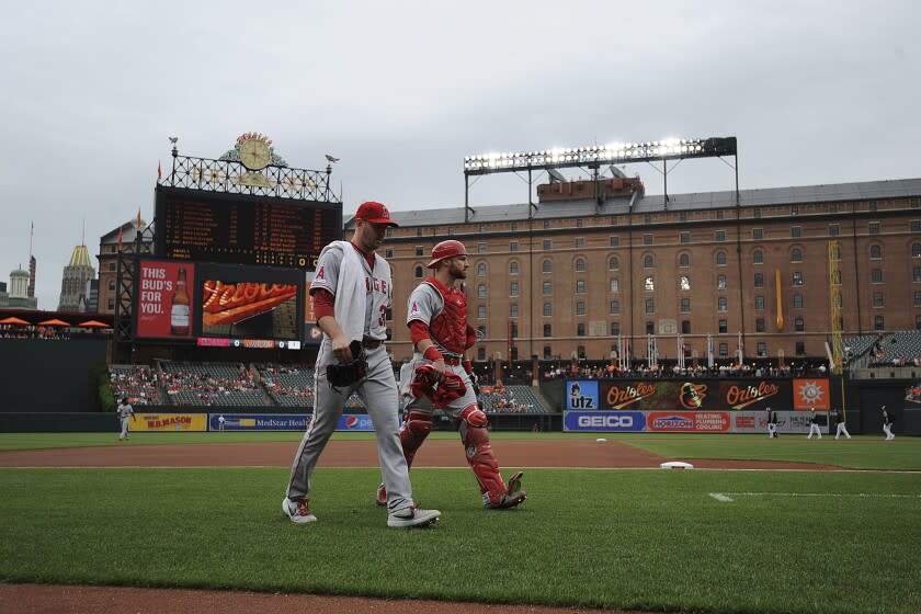 Los Angeles Angels' Matt Harvey, left, and Jonathan Lucroy walk to the dugout before playing the Baltimore Orioles in a baseball game, Saturday, May 11, 2019, in Baltimore. (AP Photo/Gail Burton)