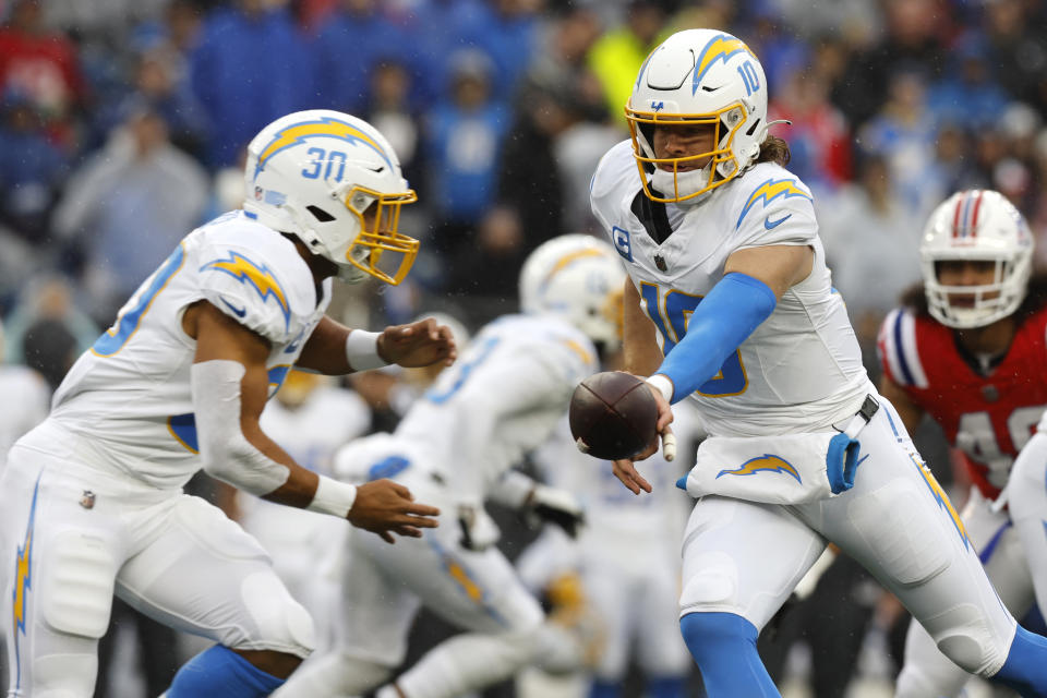 Los Angeles Chargers quarterback Justin Herbert (10) hands off to running back Austin Ekeler (30) during the first half of an NFL football game against the New England Patriots, Sunday, Dec. 3, 2023, in Foxborough, Mass. (AP Photo/Michael Dwyer)