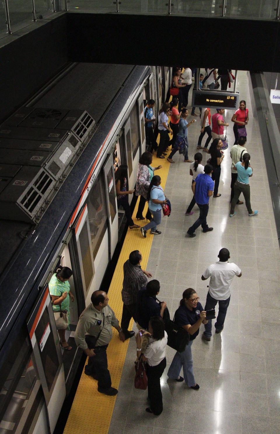 In this Wednesday, April 2, 2014 photo, government employees and their guests disembark from a subway while participating in an invitation to test the wagons of the new Panama Metro in Panama City. Central America’s first underground metro will surely alleviate the booming capital’s dreadful traffic. But critics say the $2 billion spent on the 14-kilometer rail project, which was marred by cost overruns, would’ve been better used building a higher-capacity, surface transport network. They also are blasting the timing of the over-the-top inauguration set for Saturday, April 5, which they say is a political stunt by President Ricardo Martinelli to drum up support for his preferred successor. (AP Photo/Arnulfo Franco)
