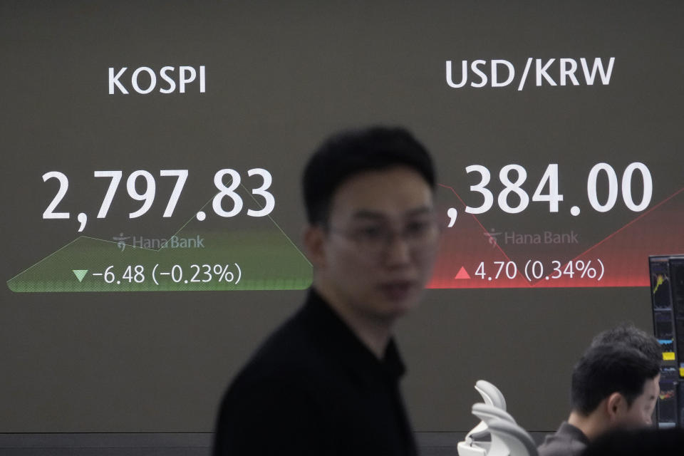 A currency trader passes by the screen showing the Korea Composite Stock Price Index (KOSPI), left, and the foreign exchange rate between U.S. dollar and South Korean won at the foreign exchange dealing room of the KEB Hana Bank headquarters in Seoul, South Korea, Tuesday, July 2, 2024. (AP Photo/Ahn Young-joon)
