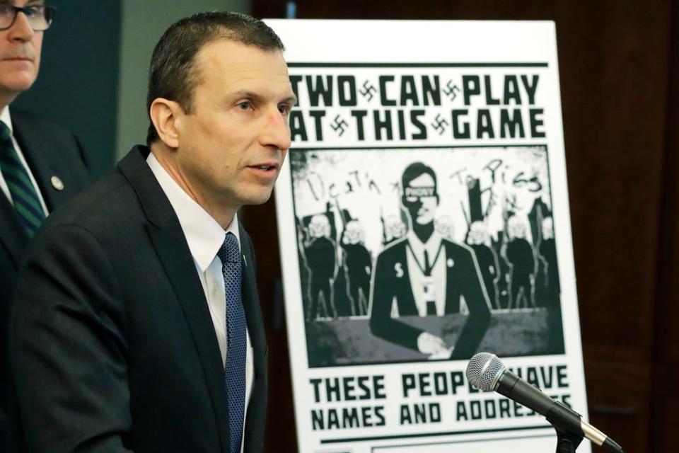 Raymond Duda, FBI Special Agent in Charge in Seattle, speaks Wednesday, as he stands next to a poster that was mailed earlier in the year to the home of Chris Ingalls, an investigative reporter with KING-TV during a news conference in Seattle. Officials charged a group of alleged members of the neo-Nazi group Atomwaffen Division for cyber-stalking and mailing threatening communications — including Swastika-laden posters — in a campaign against journalists in several cities.