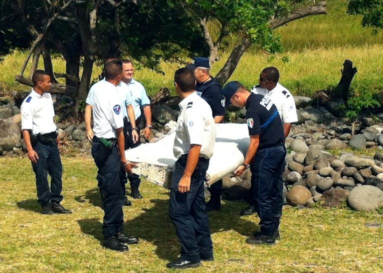 Police and gendarmes carry a piece of debris from an unidentified aircraft found in the coastal area of Saint-Andre de la Reunion, in the east of the French Indian Ocean island of La Reunion, on July 29, 2015