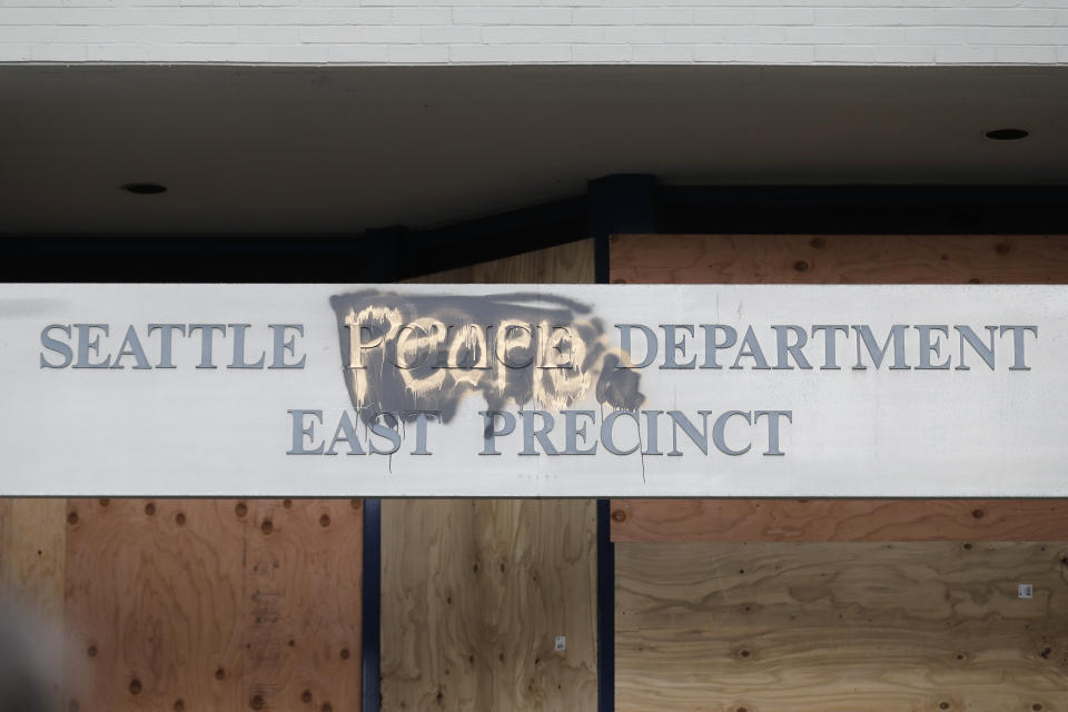 A modified sign for the Seattle Police Dept. East Precinct building, which has been boarded up and abandoned except for a few officers inside, is shown, Thursday, June 11, 2020, inside what is being called the "Capitol Hill Autonomous Zone" in Seattle. (AP Photo/Ted S. Warren)