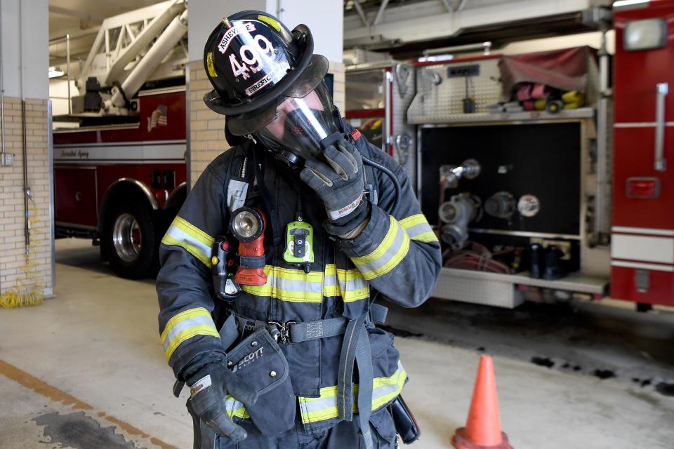 Matthew Kaylor connects his oxygen tank to his mask as he demonstrates how much gear a firefighter wears when called out to a fire. For years firefighters have been making efforts to protect their lungs from the carcinogens in smoke but only recently have started worrying about exposure through their skin and contaminated gear. 