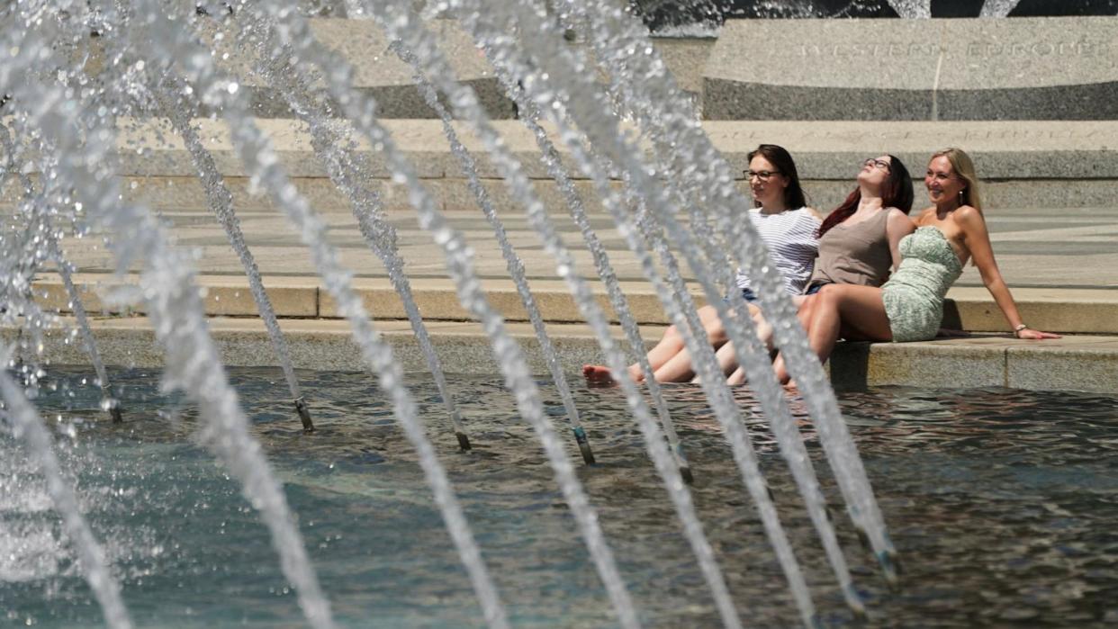 PHOTO: Women dip their feet in the cool fountain at the World War II Memorial on a possible record setting heat day in Washington, D.C., April 29, 2024.  (Kevin Lamarque/Reuters)